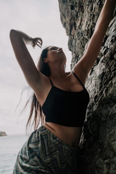 A girl climbs a rock. The athlete trains in nature. Woman overcomes difficult climbing route. Extreme hobby. Tourist woman rock climber hiking on mountains rocks over beautiful sea coast