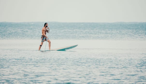 Asian man swimming in sea water and paddleboarding passing beautiful sea at summer sunset. Healthy strong male enjoy outdoor active lifestyle and water sports on holiday vacation