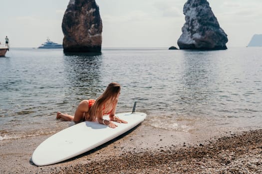 Close up shot of beautiful young caucasian woman with black hair and freckles looking at camera and smiling. Cute woman portrait in a pink bikini posing on a volcanic rock high above the sea