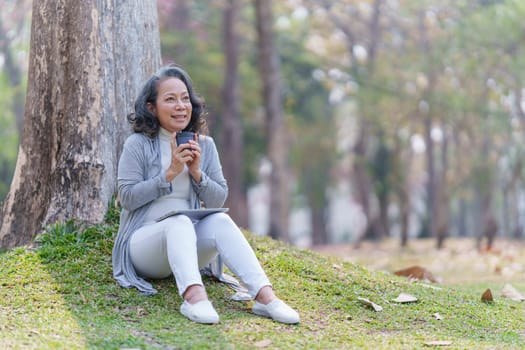 Cheerful overjoyed woman happy and enjoying peaceful beautiful in park and holding hot coffee.