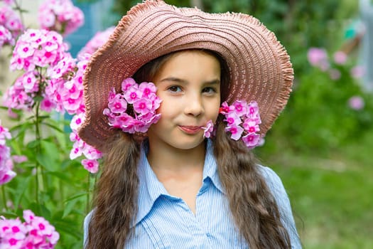 cute little girl in hat with pink phlox flowers, summer. Close up