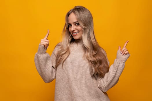 young european woman reporting news on the wall against studio orange background.