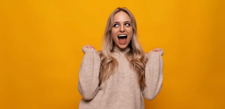 caucasian young woman emotionally rejoices among yellow background.