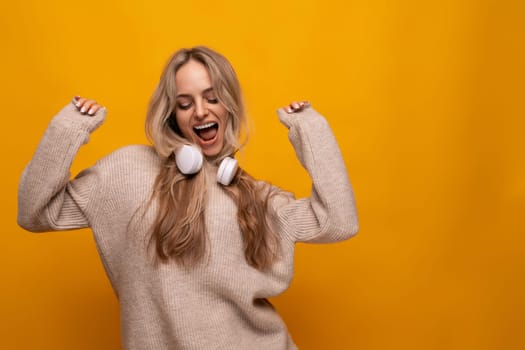 cute lady with headphones around her neck smiling on a yellow background.