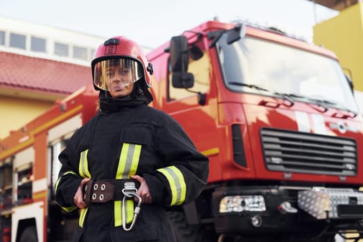 Female firefighter in protective uniform standing near truck.