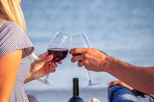 Romantic couple enjoying wine by the sea. Selective focus