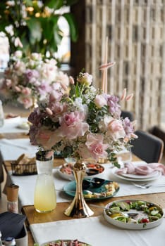 served table in the restaurant is decorated with a luxurious bouquet. Garden roses, eustoma, populus eucalyptus. pastel colours.