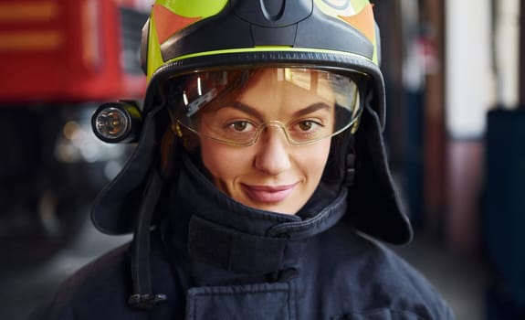 Close up view. Female firefighter in protective uniform standing near truck.