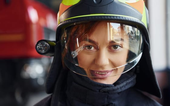 Close up view. Female firefighter in protective uniform standing near truck.