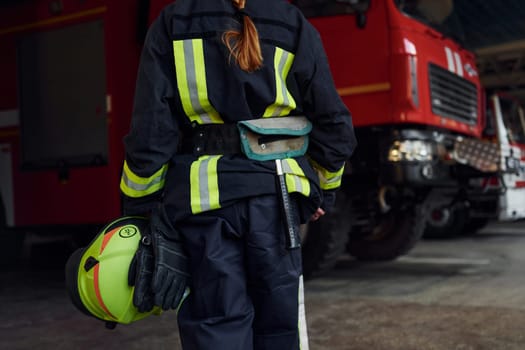 Close up view. Female firefighter in protective uniform standing near truck.