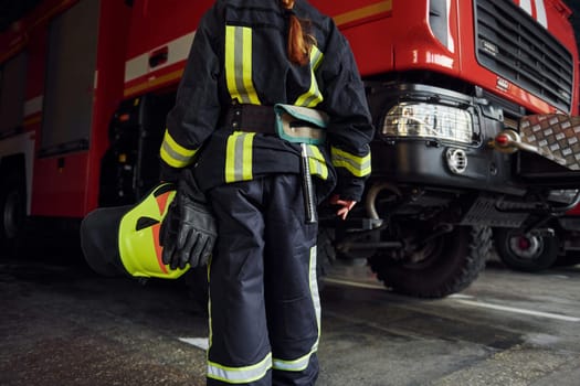 Close up view. Female firefighter in protective uniform standing near truck.