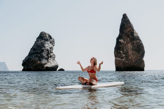 Close up shot of beautiful young caucasian woman with black hair and freckles looking at camera and smiling. Cute woman portrait in a pink bikini posing on a volcanic rock high above the sea