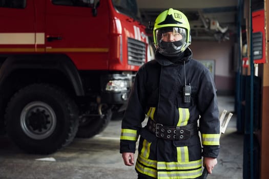 Male firefighter in protective uniform standing near truck.