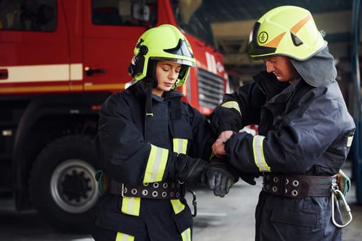 Male and female firefighters in protective uniform standing together.