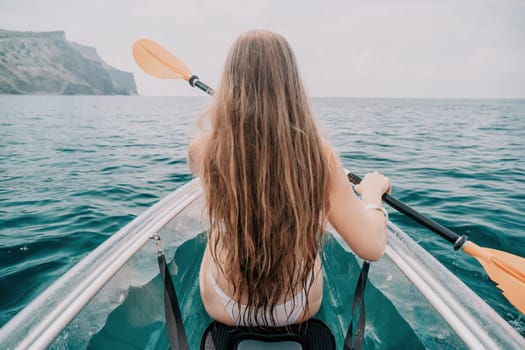 Woman in kayak back view. Happy young woman with long hair floating in transparent kayak on the crystal clear sea. Summer holiday vacation and cheerful female people having fun on the boat.