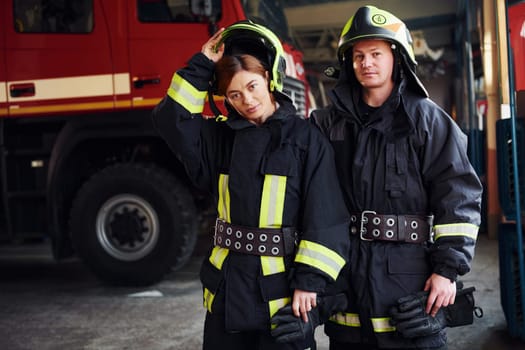 Male and female firefighters in protective uniform standing together.