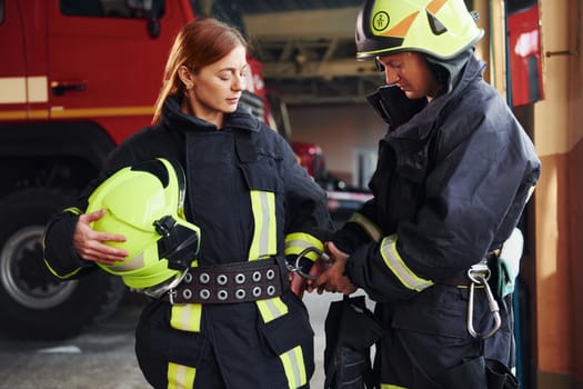 Male and female firefighters in protective uniform standing together.