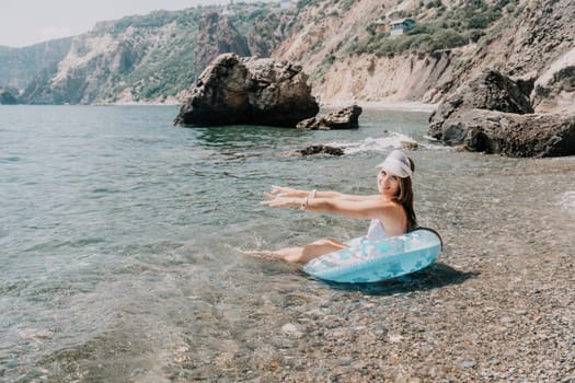 Woman summer sea. Happy woman swimming with inflatable donut on the beach in summer sunny day, surrounded by volcanic mountains. Summer vacation concept