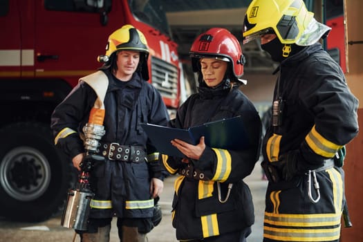 With notepad. Group of firefighters in protective uniform that is on station.