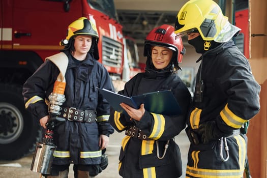 With notepad. Group of firefighters in protective uniform that is on station.