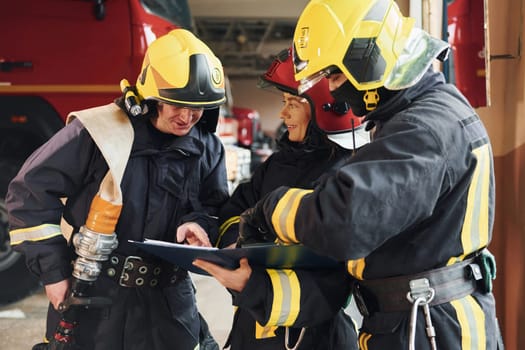 With notepad. Group of firefighters in protective uniform that is on station.