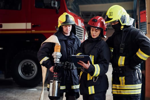 With notepad. Group of firefighters in protective uniform that is on station.