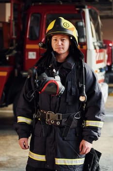 Female firefighter in protective uniform standing near truck.