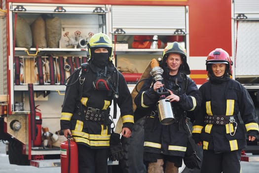 Group of firefighters in protective uniform that outdoors near truck.