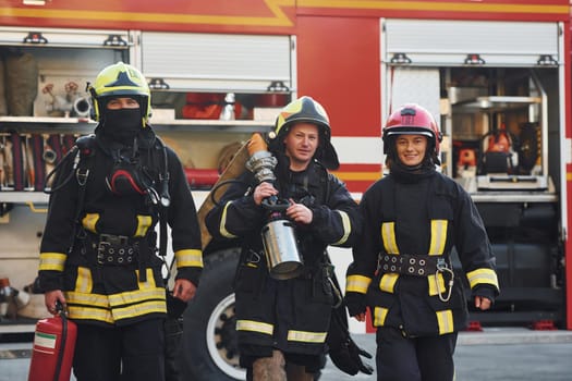 Group of firefighters in protective uniform that outdoors near truck.