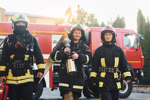 Group of firefighters in protective uniform that outdoors near truck.