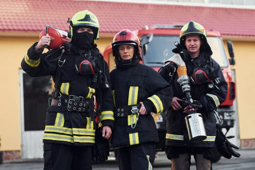 Group of firefighters in protective uniform that outdoors near truck.