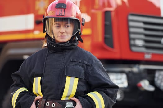 Female firefighter in protective uniform standing near truck.