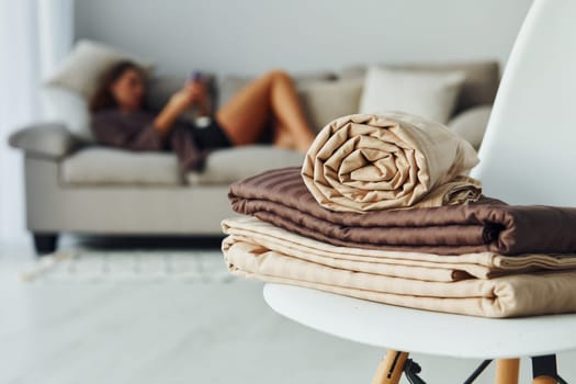 Girl lying down on the bed with smartphone. Interior and design of beautiful modern bedroom at daytime.