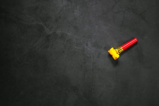 Birthday party blowouts whistles Rolled festive noisemaker or party whistle on concrete dark background, blowing in whistle top view in and out loop 4k Happy Birthday copy space