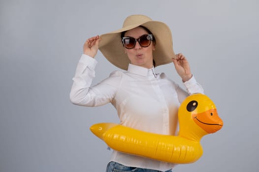 Excited woman dreaming about vacation, wearing sunglasses, hat and inflatable duck