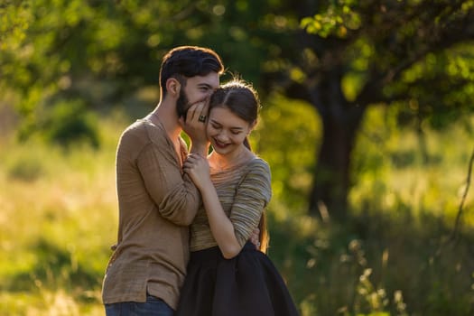 man tells in his ear the secret of his girlfriend walking in the park