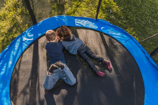 children look at the phone while lying on a trampoline, top view