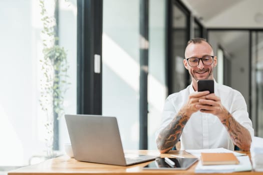 Portrait of a cheerful man using smart phone at home office..