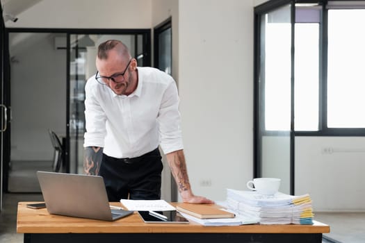 Businessman using laptop computer in office. Happy middle aged man, entrepreneur, small business owner working online..