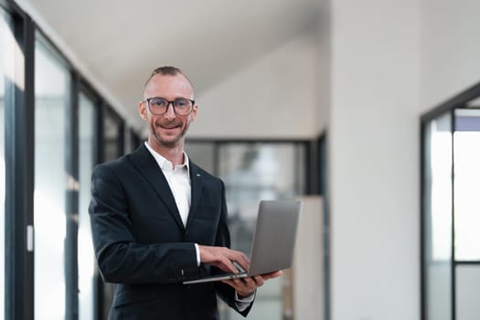 businessman handsome smiling using laptop while standing in office.