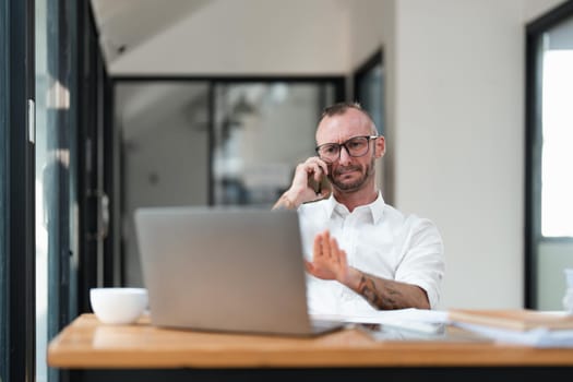 Accountant or bookkeeper using laptop computer while talking smartphone with accountant consult and for calculating tax, financial report.