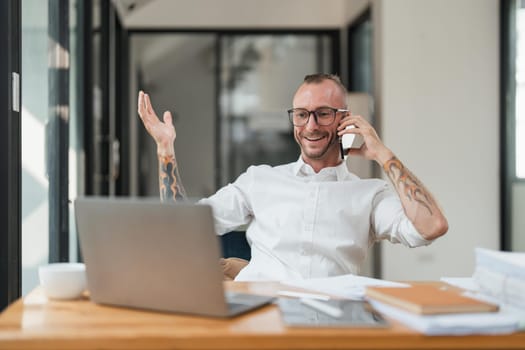 Accountant or bookkeeper using laptop computer while talking smartphone with accountant consult and for calculating tax, financial report.