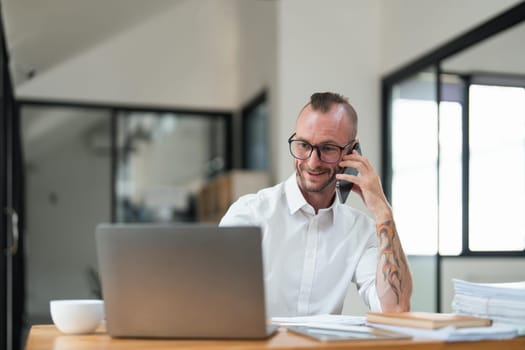 Accountant or bookkeeper using laptop computer while talking smartphone with accountant consult and for calculating tax, financial report.