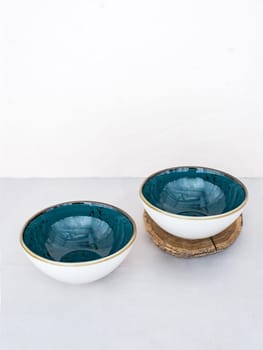 Two empty blue soup bowlson table on white background for your copy. Two blue handmade ceramic soup plates