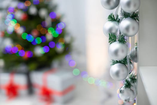 Silver ribbon baubles on a spruce branch on a fuzzy background room decoration .