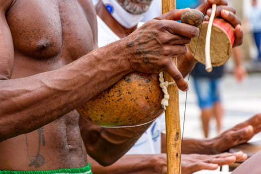African-American musician playing a traditional Brazilian percussion instrument called berimbau during a capoeira performance on the streets of Pelourinho in Salvador, Bahia