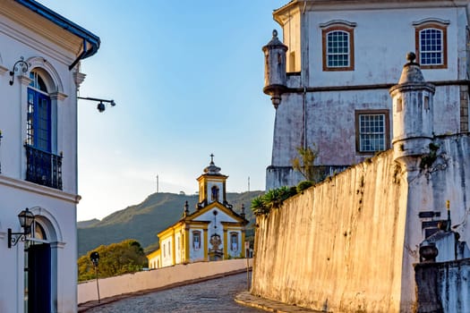 Arrival in the historic center of Ouro Preto with colonial style houses, monuments, churches and old buildings with hills in background at sunset