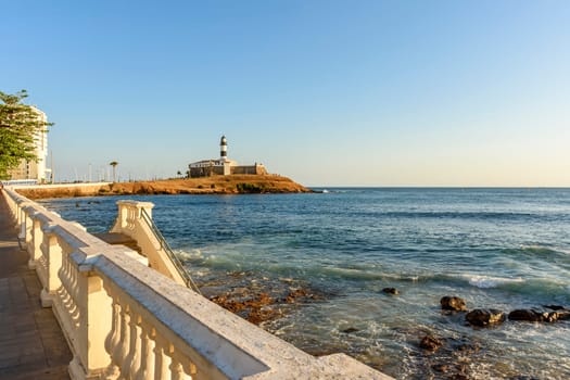 Barra Lighthouse (Farol da Barra) one of the main historical buildings and tourist spot in the city of Salvador in Bahia surrounded by the sea during the late afternoon.