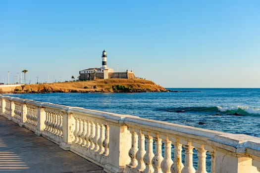 Barra Lighthouse (Farol da Barra) one of the main historical buildings and tourist spot in the city of Salvador in Bahia surrounded by the sea during the late afternoon.