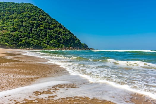 Beautiful deserted beach in Bertioga on the coast of São Paulo state, Brazil with the hill and rainforest in the background